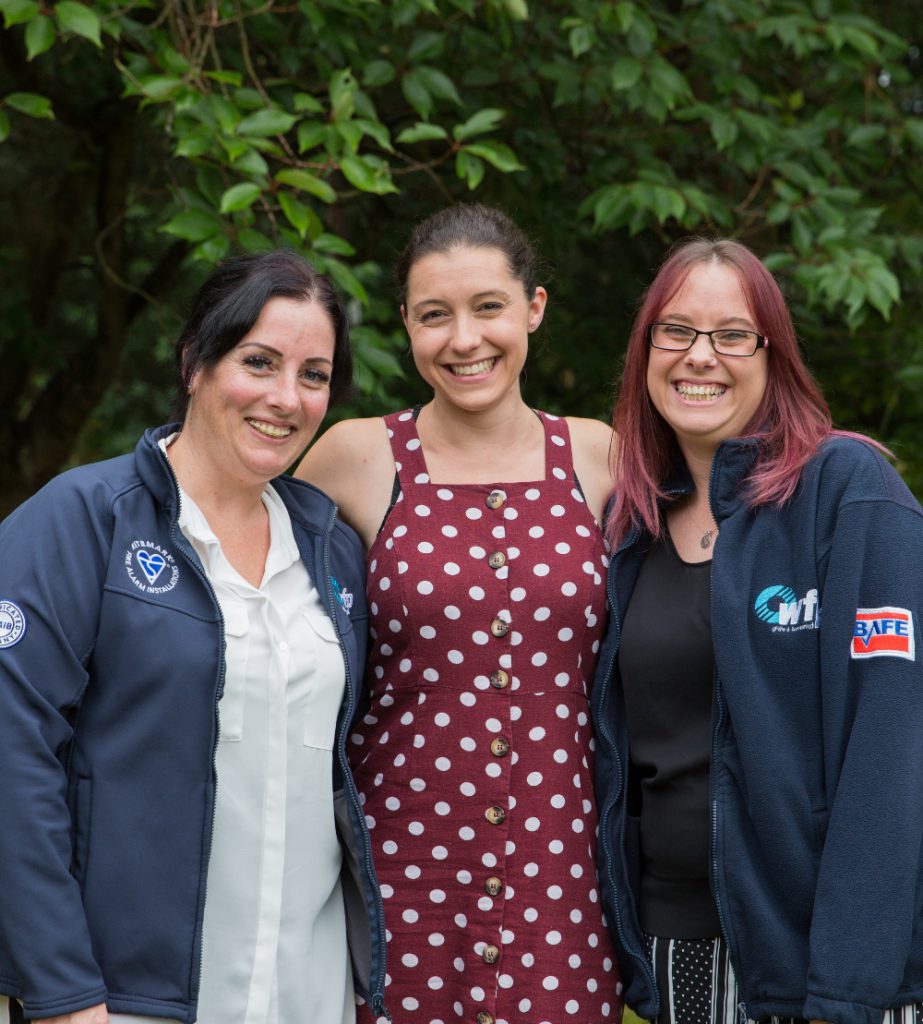 Three women smiling at the camera in WFP uniform